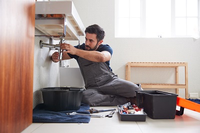 man fixing sink in bathroom